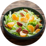 Een frisse salade met knapperige groene bladeren, sappige mandarijnpartjes en knapperige pecannoten, geserveerd in een donkergroene kom op een houten tafel.